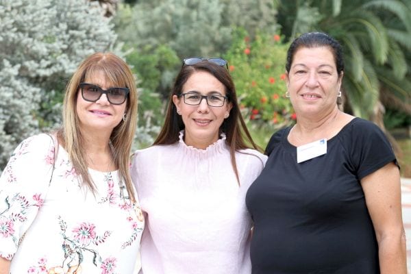 שלוש נשים מחובקות מחייכות למצלמה