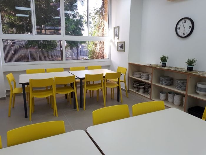 פנים הצהרון, שולחנות לבנים וכסאות צהובים שעון קיר גדול