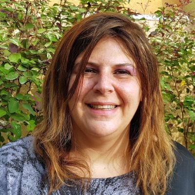 תמונת פנים אישה מחייכת על רקע צמחיה