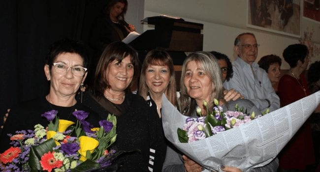 יפה ביטון מטפלת מעון נווה זאב באר שבע לצד נשים נוספות אוחזת בזר פרחים