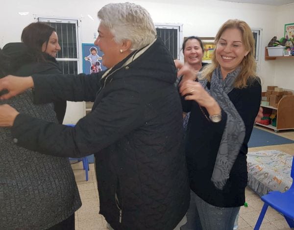 נשים עומדות בשרשרת שכל אחת מדביקה לגב חברתה פתק