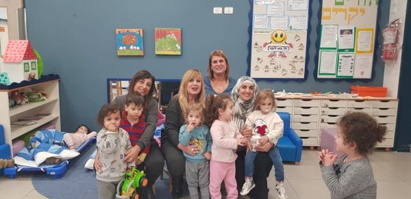 נשים יושבות ועל ברכיהן ילדים