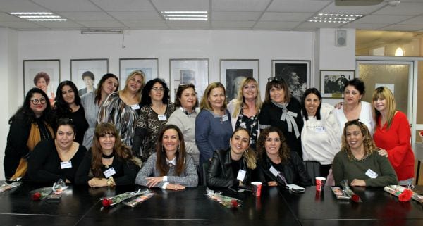 נשים חלקן יושבות ליד שולחן ארוך וחלקן עומדות מעל