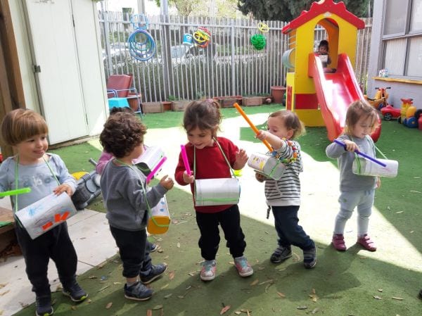 ארבעה ילדים בחצר מנגנים בכלי נגינה מאולתרים