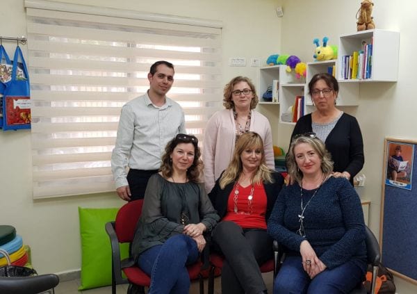 שלוש נשים יושבות ושתי נשים וגבר עומדים מאחוריהם